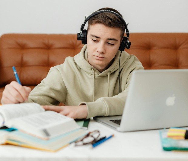 A Boy Using a Headphone While Studying