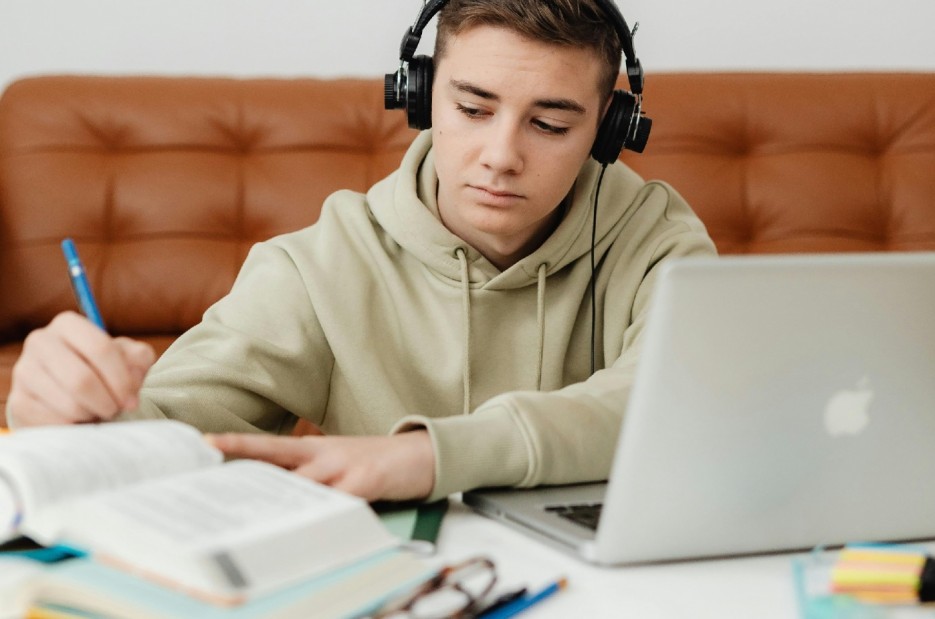 A Boy Using a Headphone While Studying
